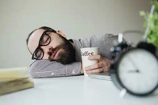 man asleep with coffee mug in his hand